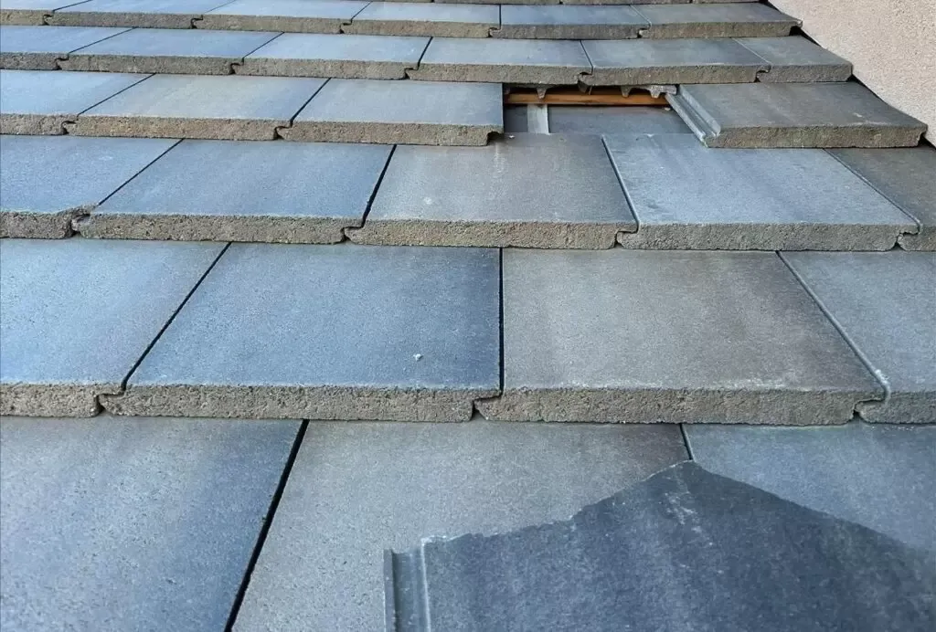 placing a tile roof piece into place where there is a missing tile on the roof