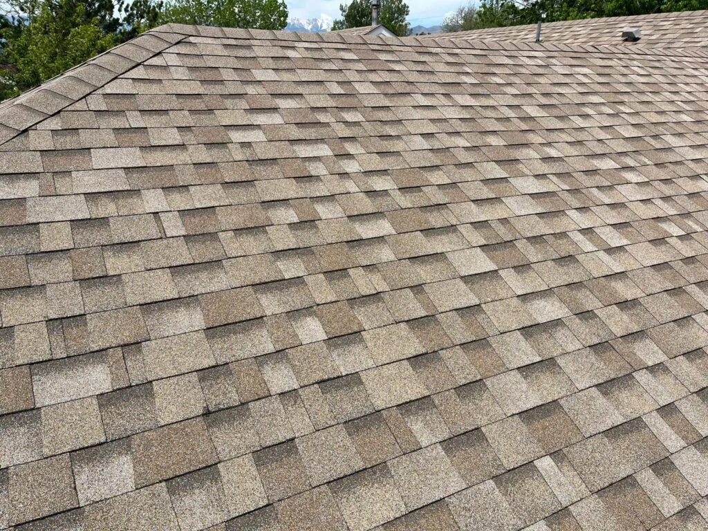 upclose of newly laid asphalt tiles on roof with different colored patches of tan for a symmetrical look