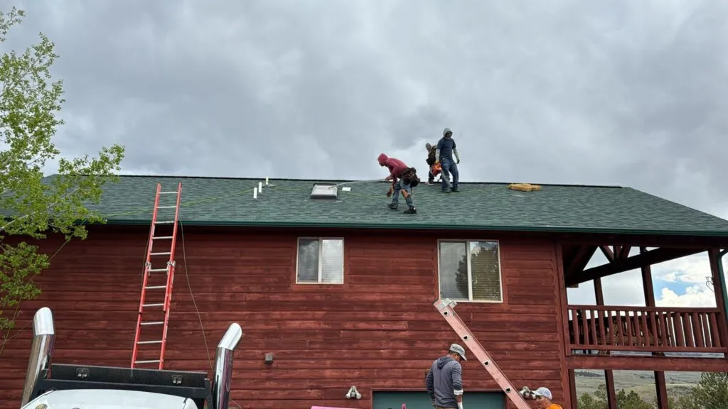 workers on roof doing last touches on a shingle roof replacement