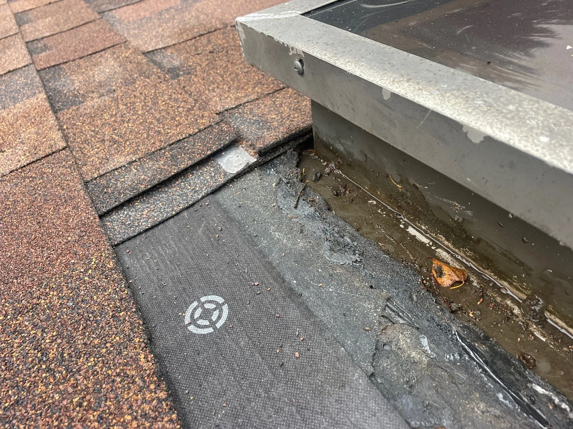water and ruined tile near a skylight on a roof in need of repair