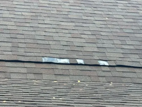 shingle tiles missing on a roof showing metal underlay